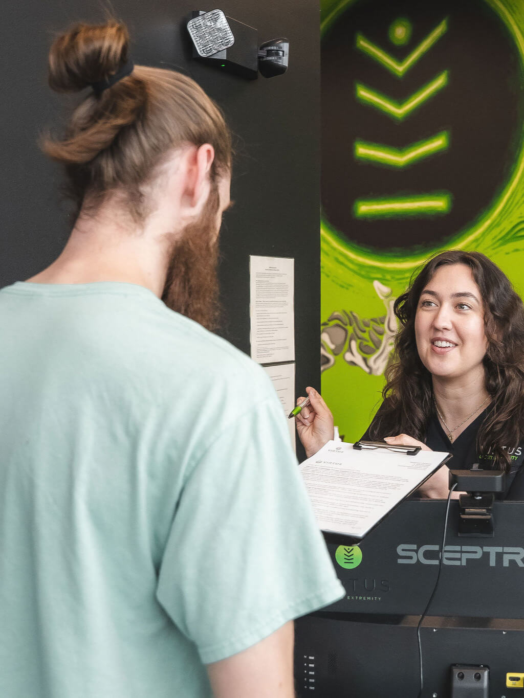 new-patients-leah-3-4 Virtus clinic staff member handing a patient a clipboard to fill out forms