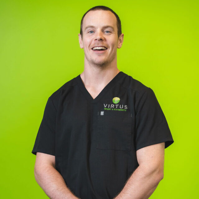jake-townsend-2026 Jake Townsend LMT smiling wearing black Virtus scrubs, professional portrait