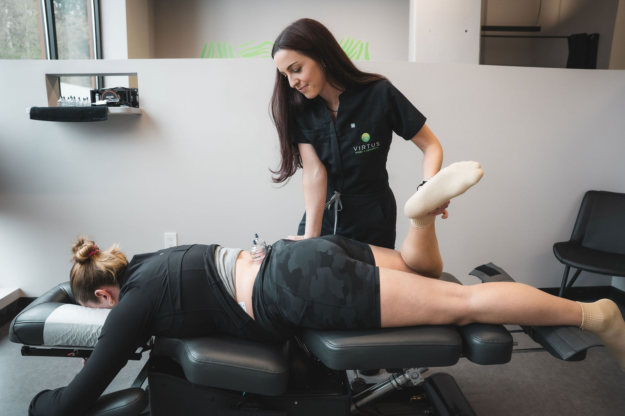 molly-sparks-patient-webster Dr. Molly Sparks using the Webster method on a patient while bending their leg and cupping on their lower back as they are laying on the adjustment table.