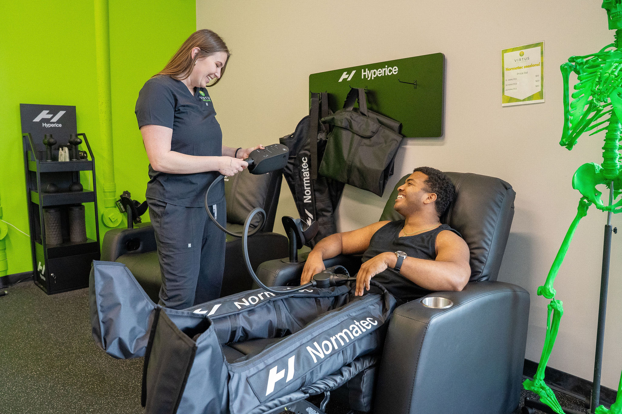 wales-nct Dr. Rylie Wales adjusting a patient's normatic compression boots while he is sitting in an armchair.